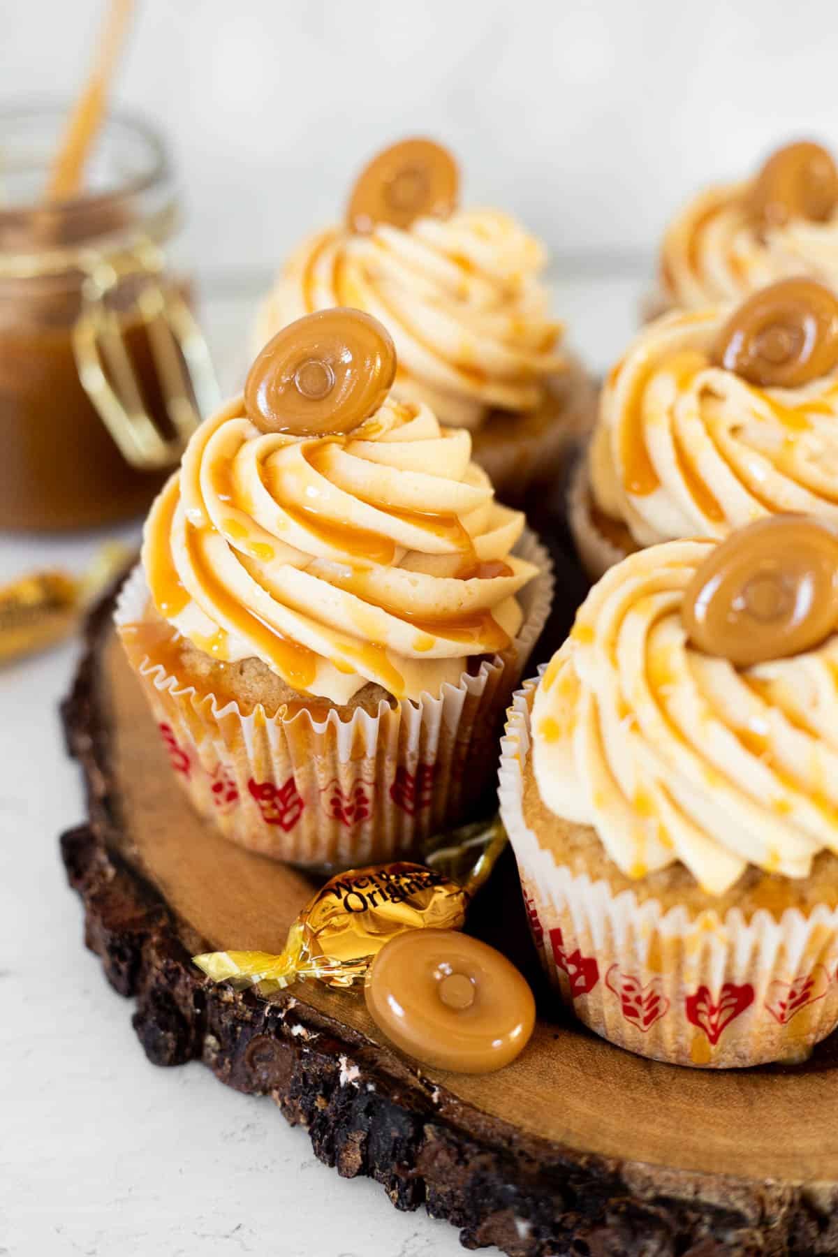 caramel filled cupcakes with buttercream and caramel drizzle on a wood board.