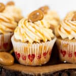 caramel filled cupcakes with drizzle and caramel candy on wooden board.