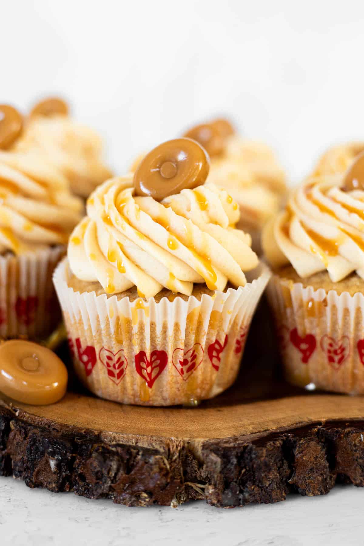 caramel filled cupcakes with drizzle and caramel candy on wooden board.