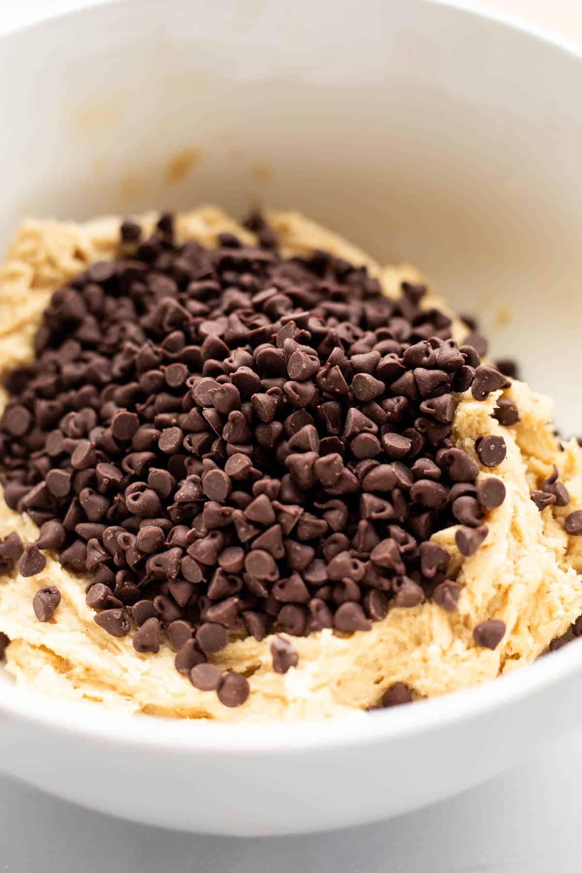 mini chocolate chips on top of cookie dough in a bowl.