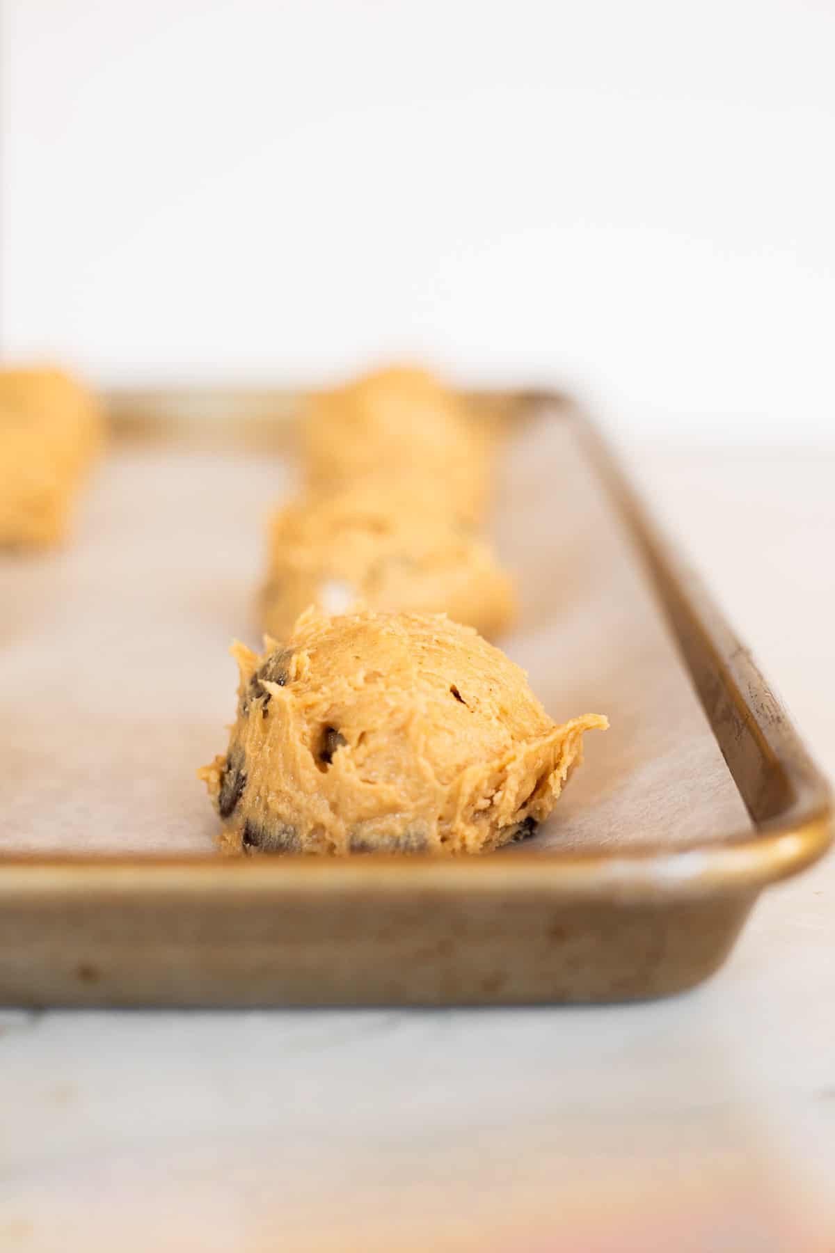 sour cream peanut butter cookie dough scooped into balls on parchment lined baking sheet.