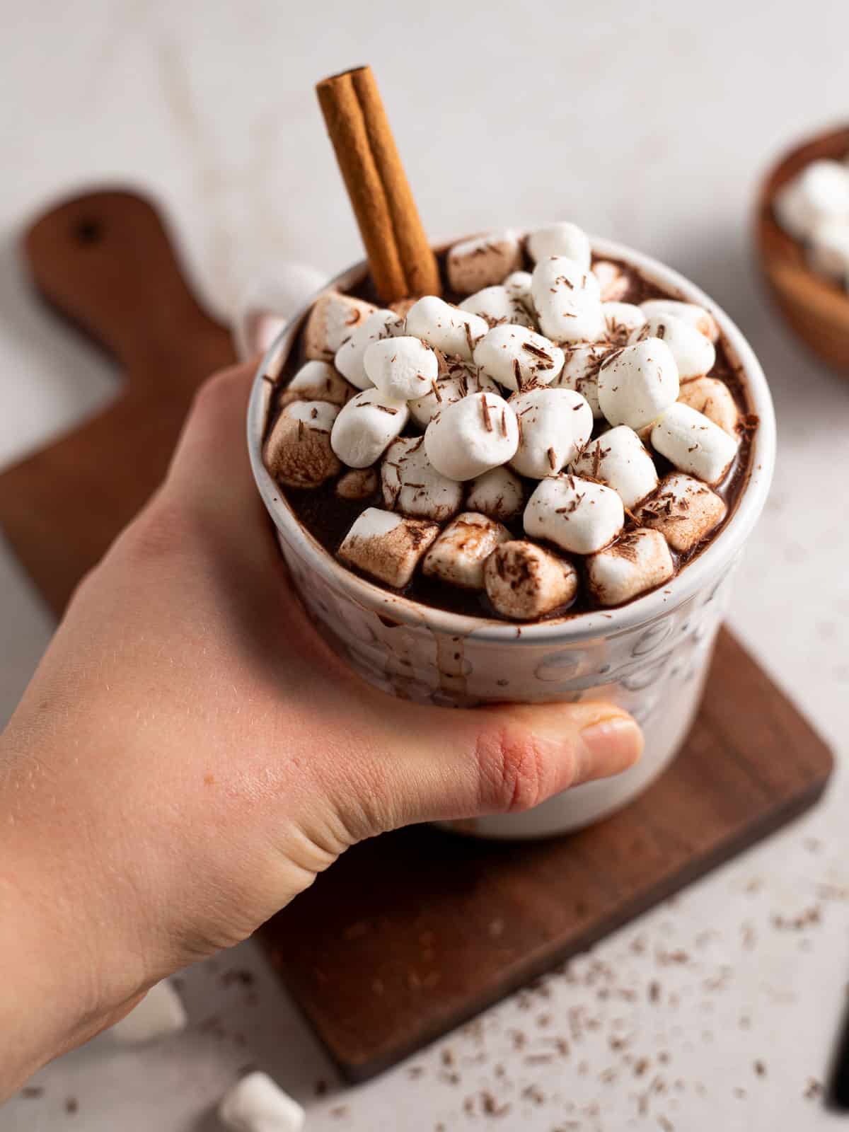 hand holding a mug of bone broth hot chocolate topped with marshmallows.