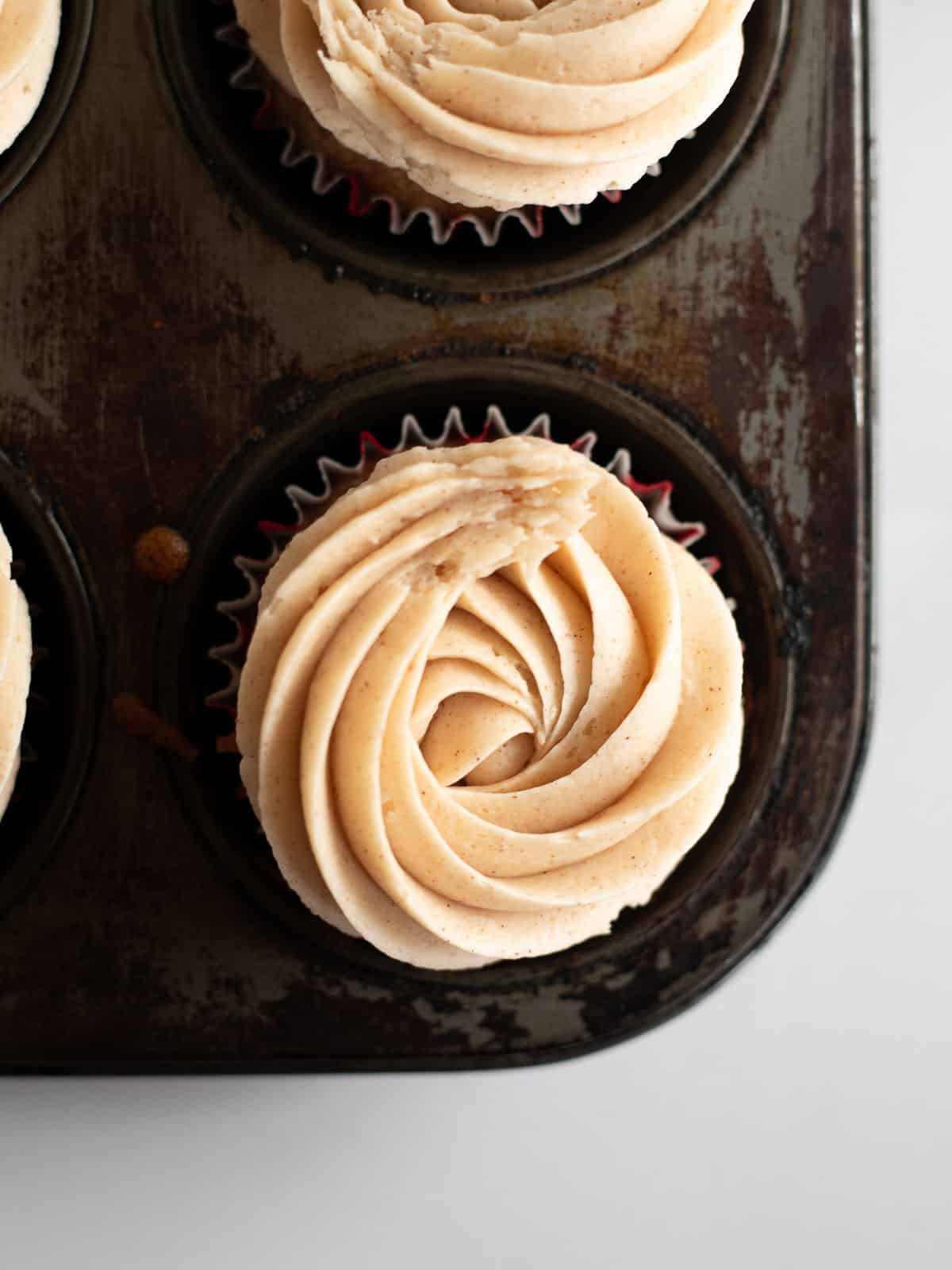 Gluten Free Gingerbread Cupcakes with cinnamon buttercream in a muffin tin.