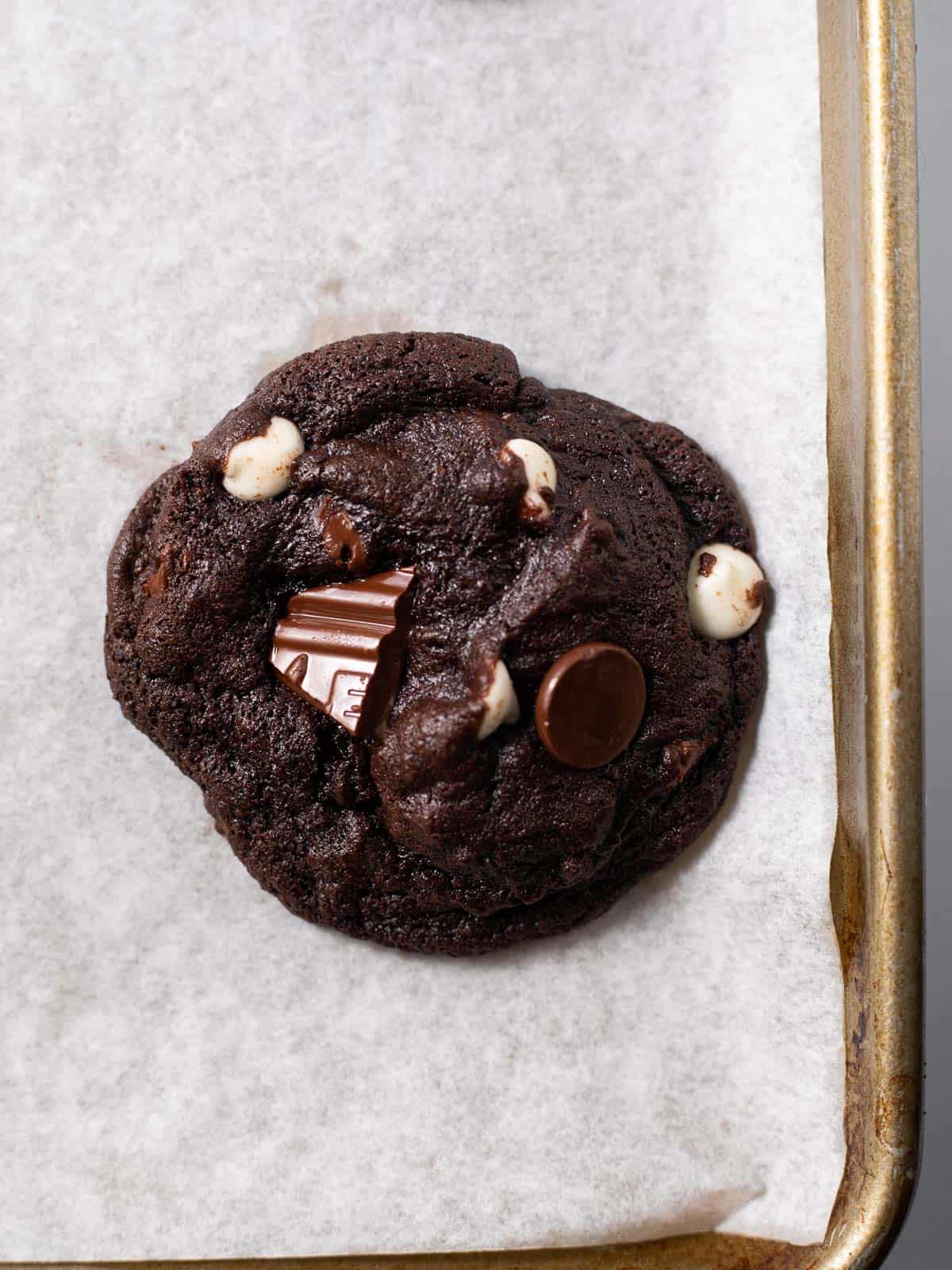a gluten free triple chocolate cookie baked on parchment paper.