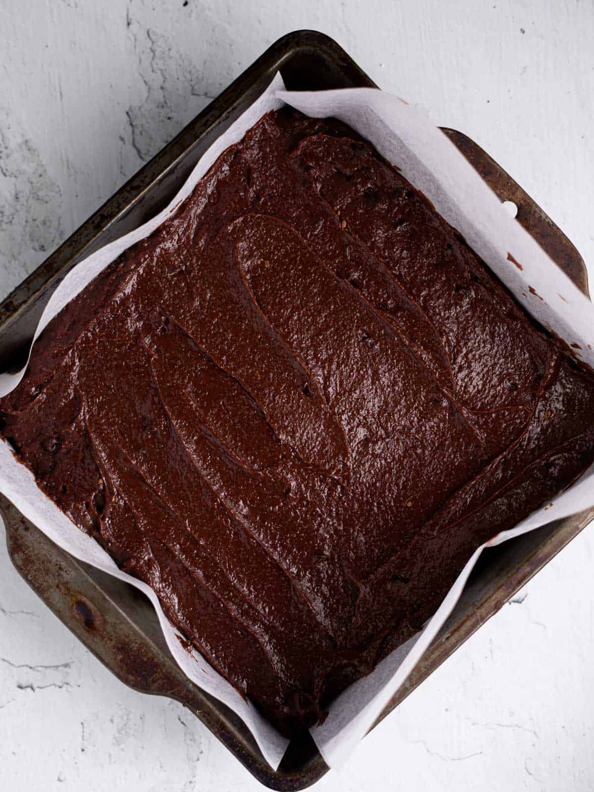 brownie batter in a parchment lined baking pan.
