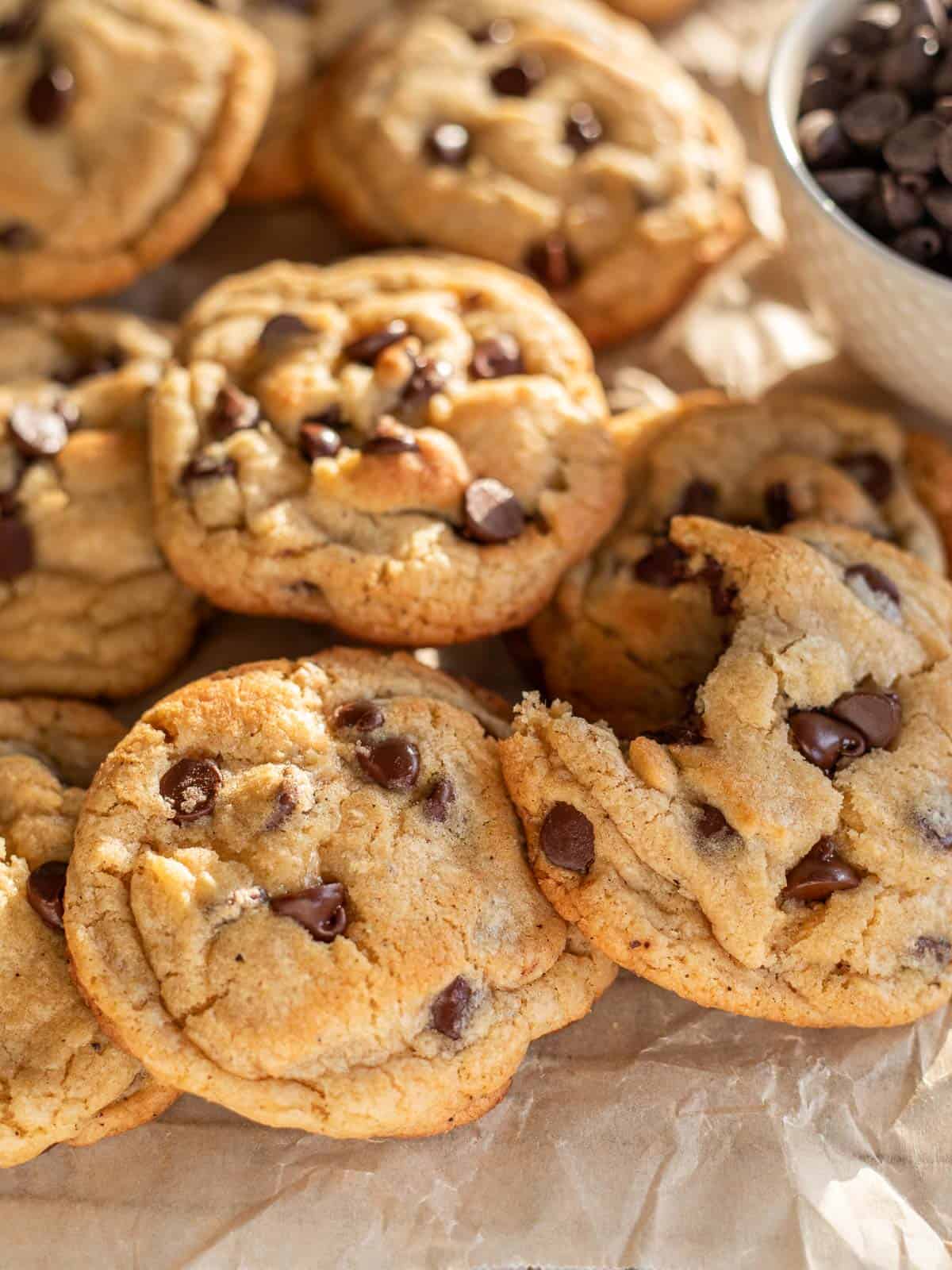 thick brown butter chocolate chip cookies piled on parchment paper.