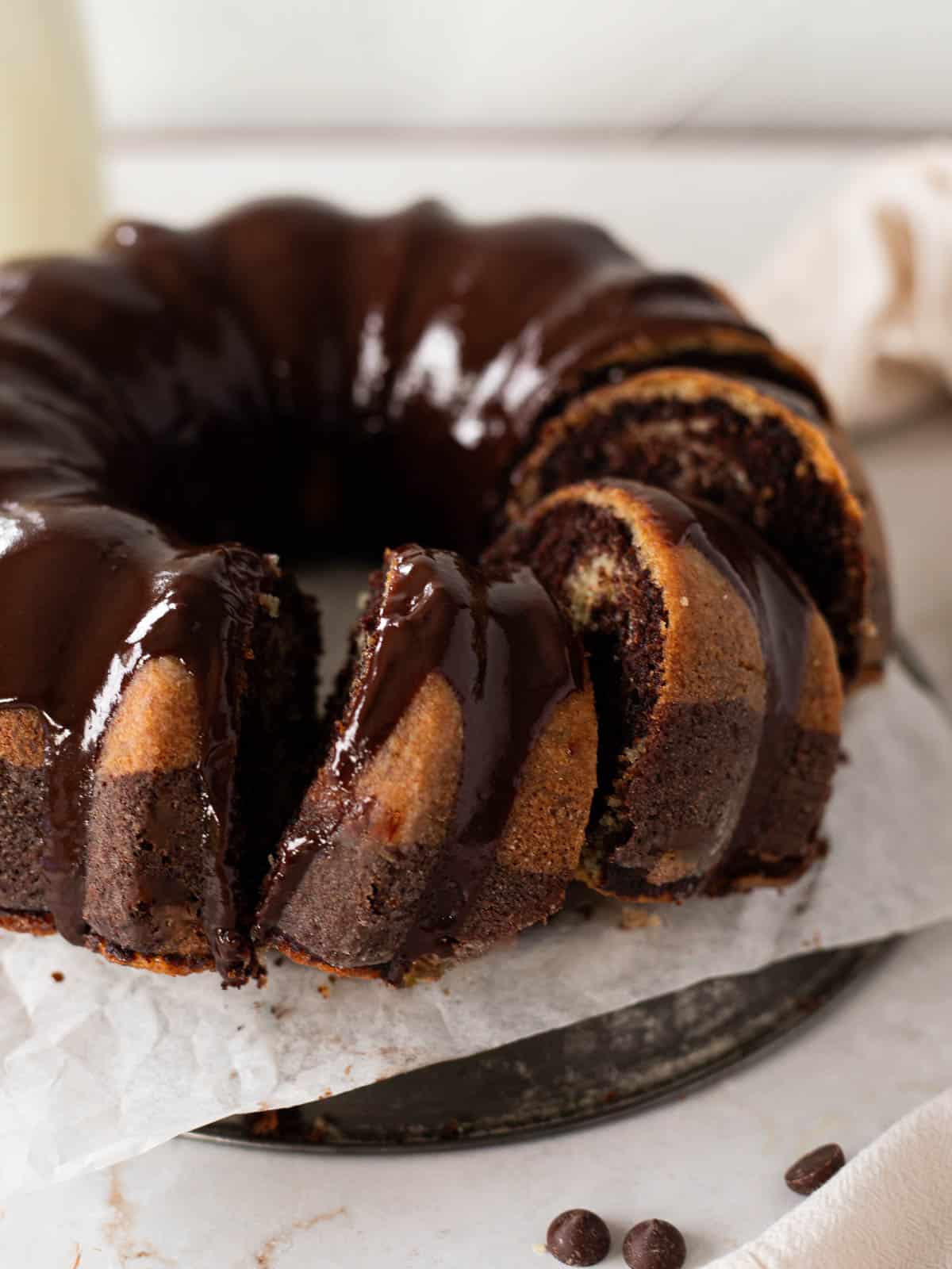buttermilk marble bundt cake with chocolate ganache with 3 slices cut into it.