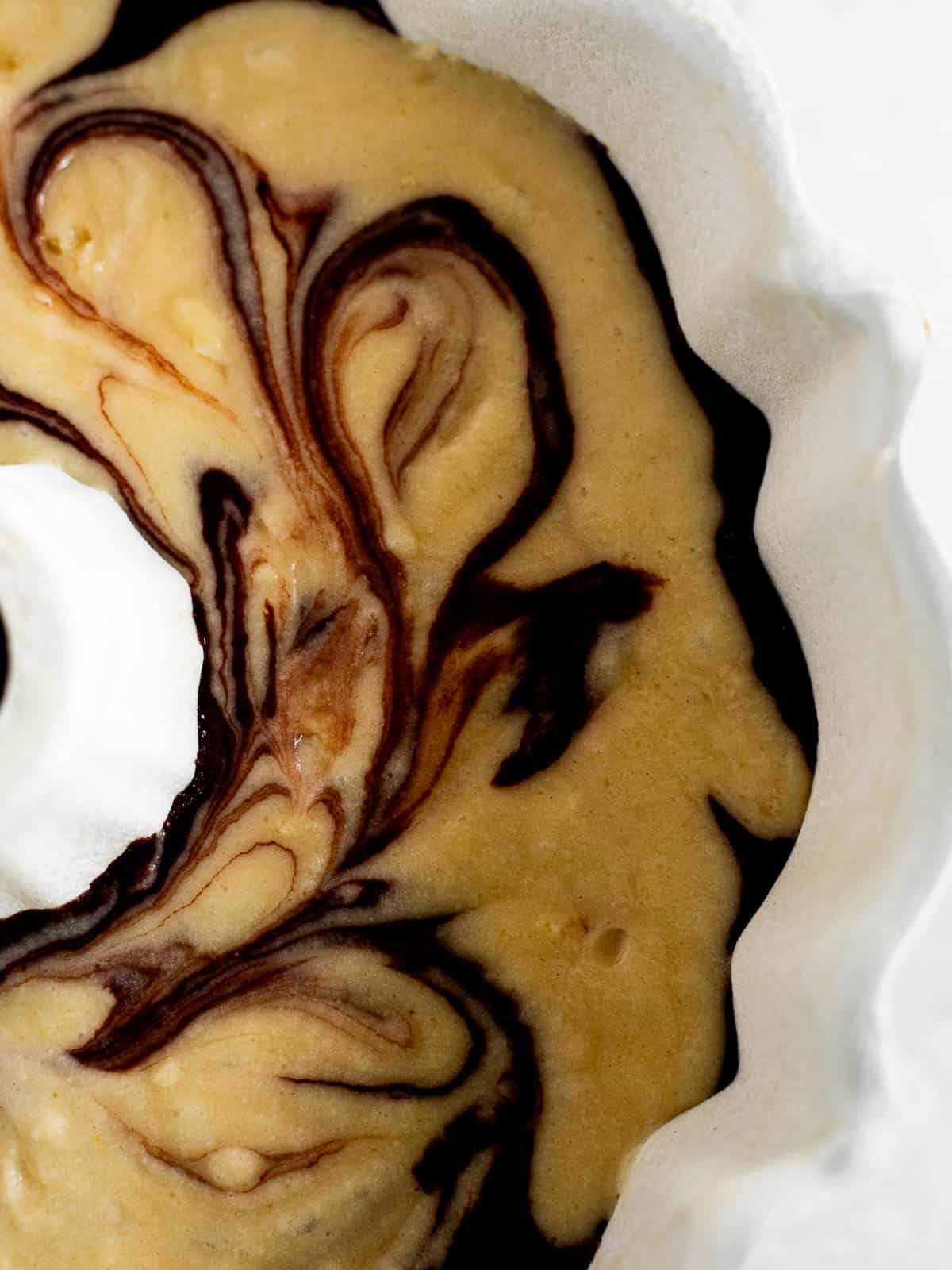 Vanilla and chocolate cake batter swirled in a white bundt pan.