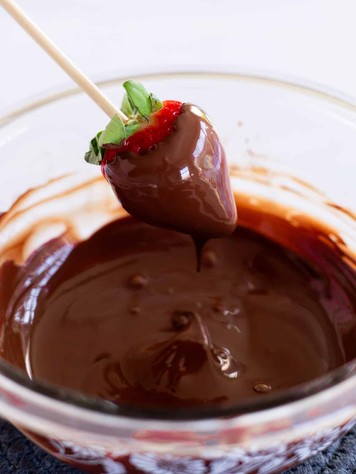a strawberry on a stick dipped in melted chocolate.