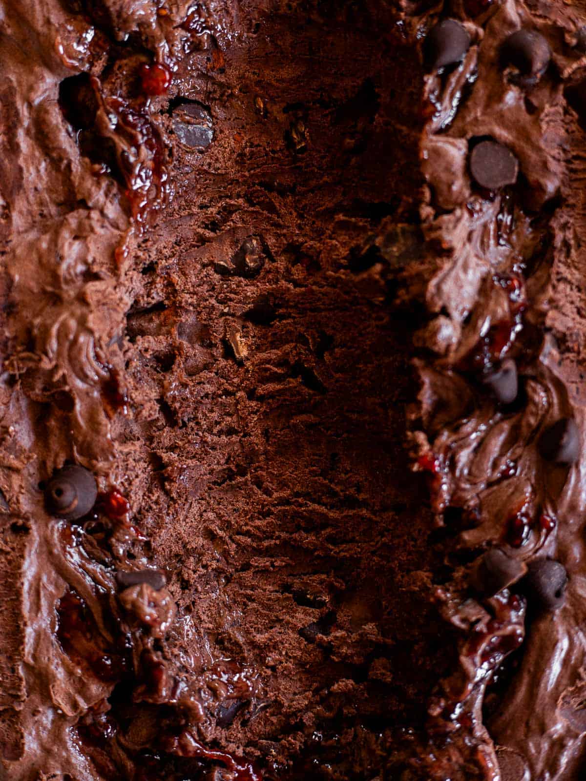 a scoop take out of a pan of raspberry dark chocolate ice cream.