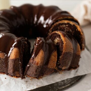 buttermilk marble bundt cake with chocolate ganache with 3 slices cut into it.