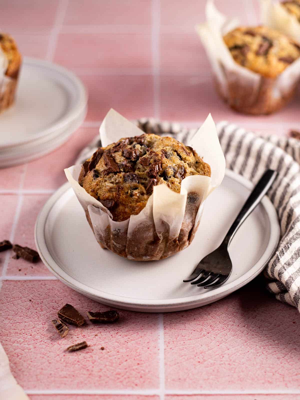 a Bakery Style Banana Chocolate Chip Muffin on a white plate with a fork.