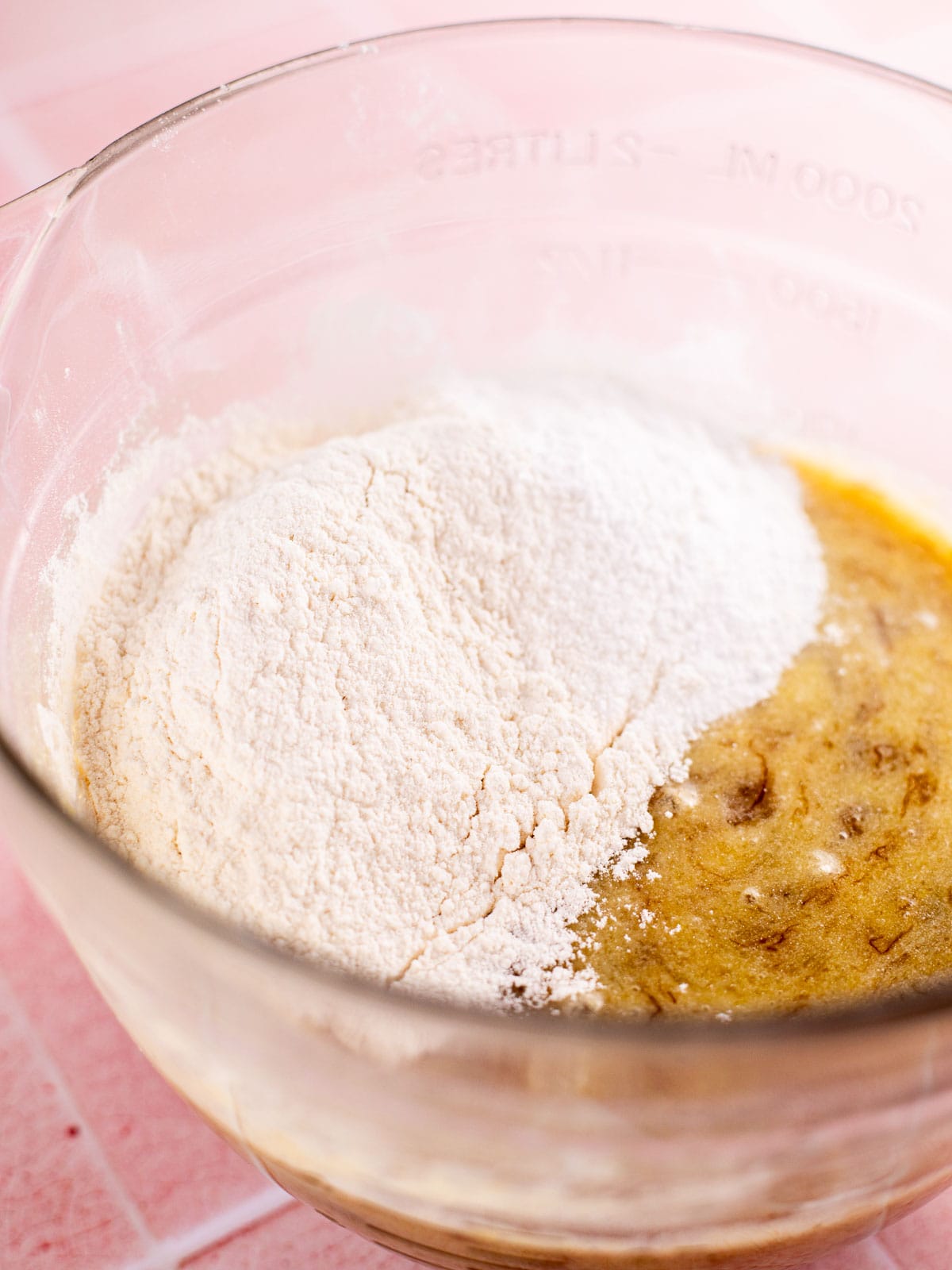 flour, salt, and baking powder in a glass bowl of wet ingredients for banana muffins.