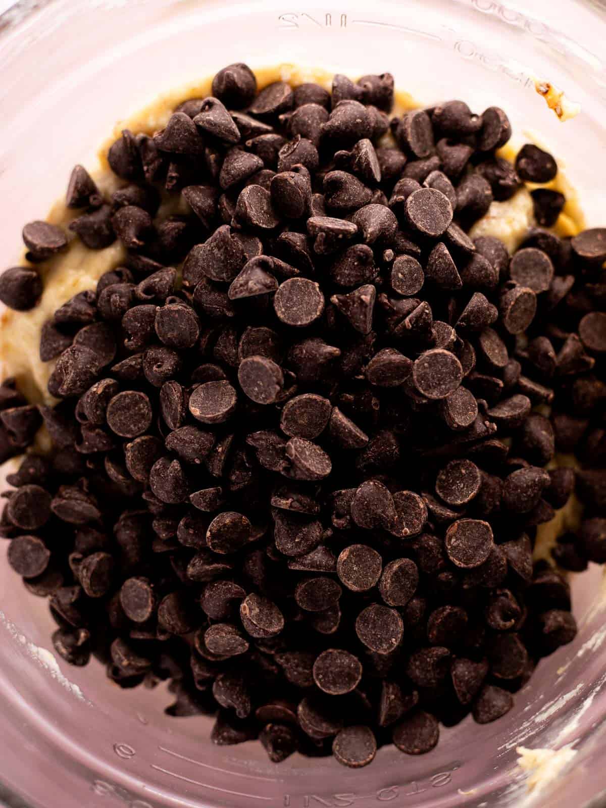 overhead photo of chocolate chips on top of banana muffin batter.