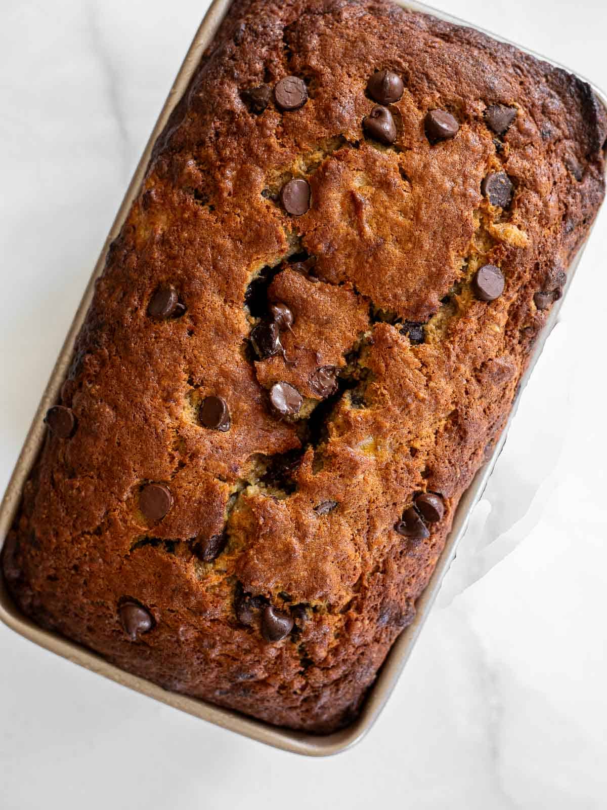 over head photo of baked brown butter banana bread with chocolate chips.