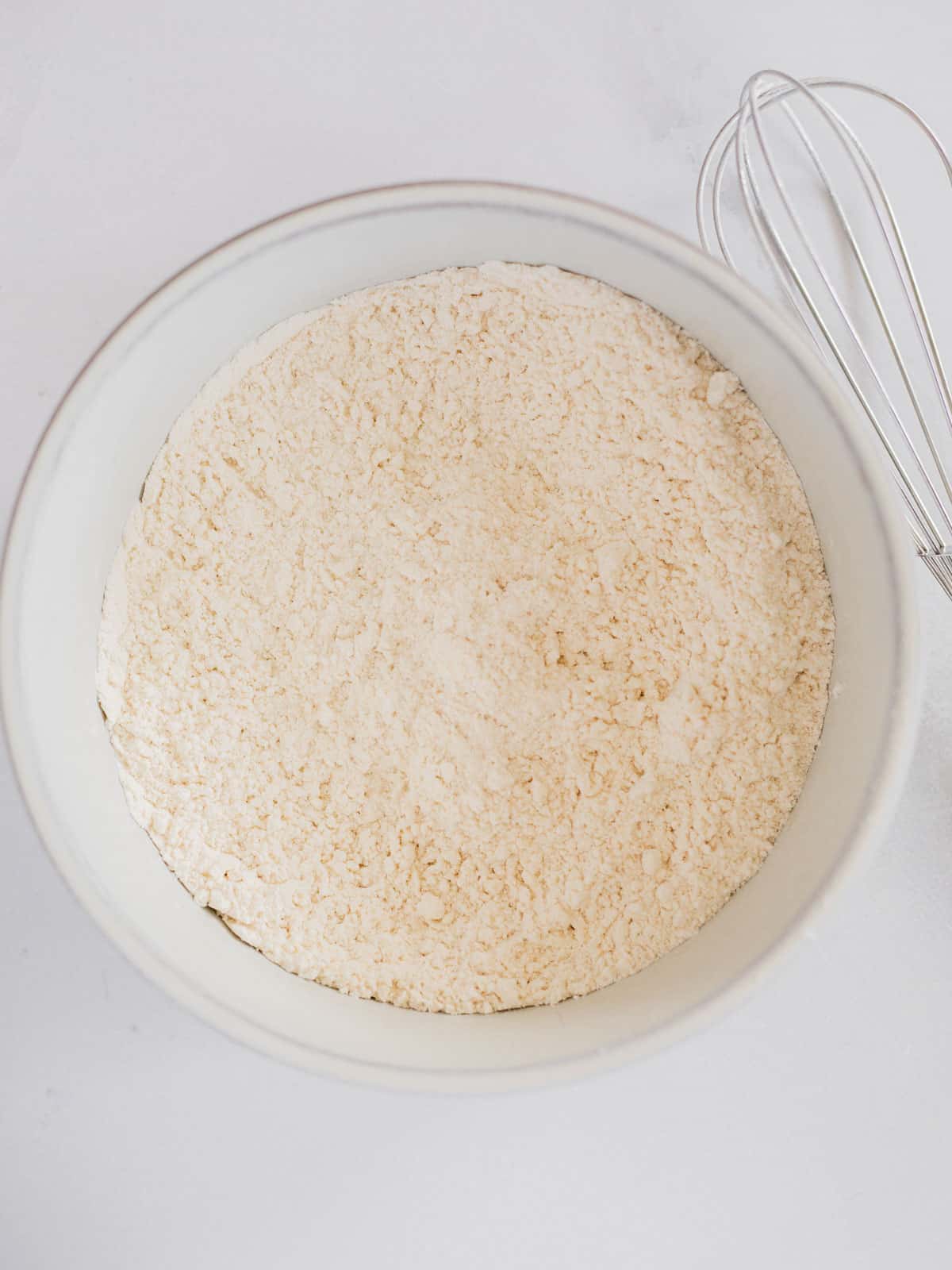 flour, baking powder, salt, and sugar in a white mixing bowl.